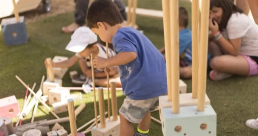 Niñas y niños jugando con las piezas de madera del juego ‘Gran Convoy’ en Matadero